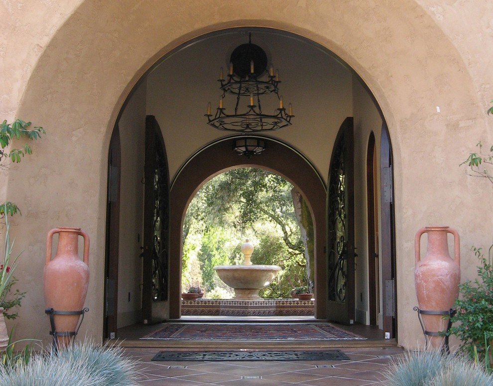 Entryway - large mediterranean terra-cotta tile entryway idea in Denver with beige walls and a glass front door