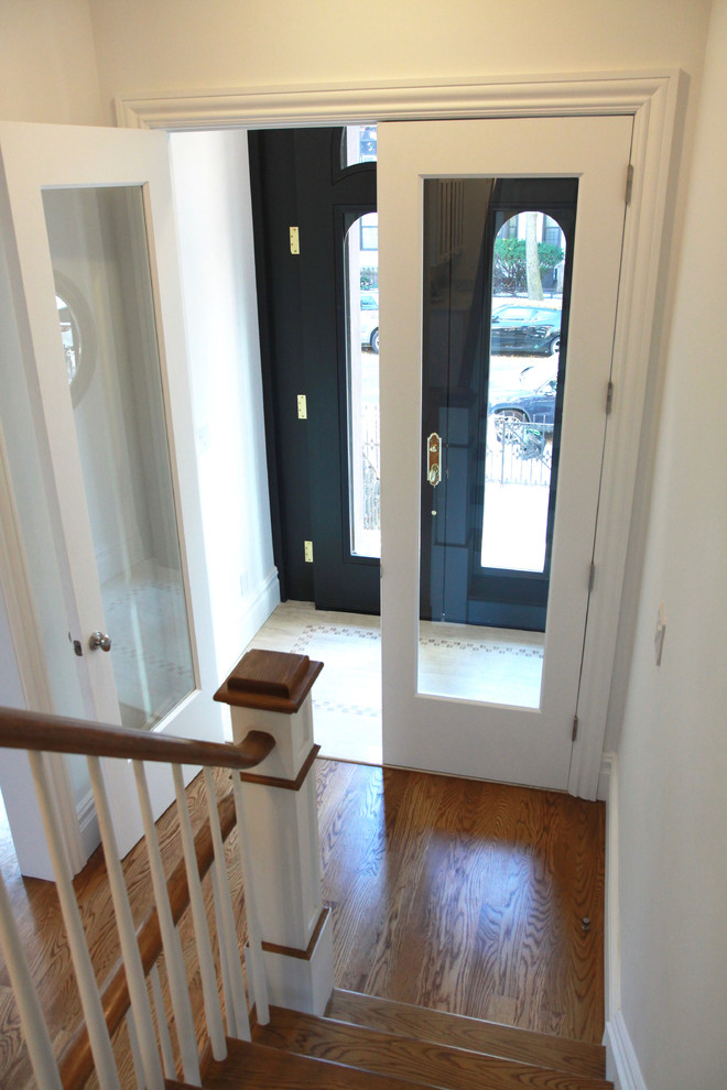 Ispirazione per un corridoio classico di medie dimensioni con pareti bianche, pavimento in legno massello medio, una porta a due ante e una porta bianca