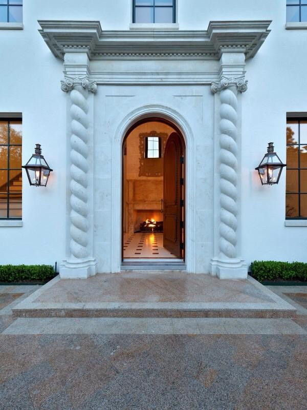 Ispirazione per una grande porta d'ingresso mediterranea con pareti bianche, pavimento in marmo e una porta in legno bruno