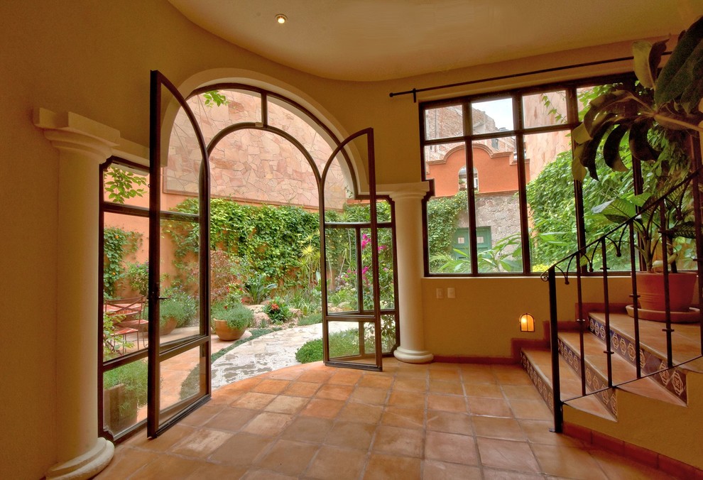 Ispirazione per un ingresso mediterraneo di medie dimensioni con pareti beige, pavimento in terracotta, una porta a due ante e una porta in vetro