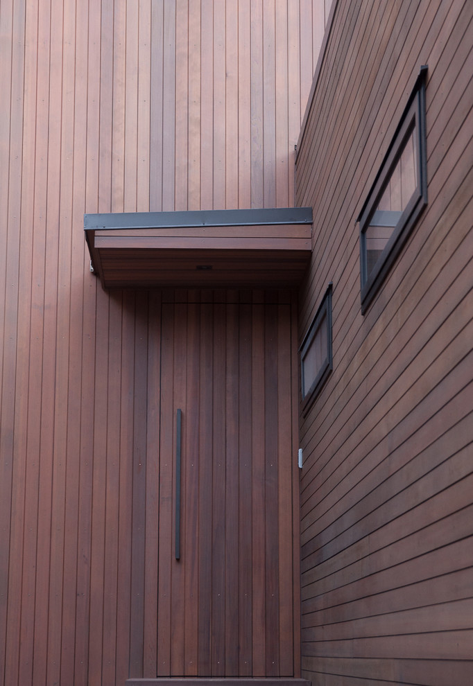 Foto på en mellanstor funkis ingång och ytterdörr, med bruna väggar, en enkeldörr och mellanmörk trädörr