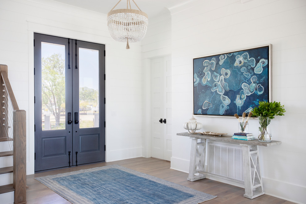 Foto di un ingresso o corridoio stile marino con pareti bianche, parquet scuro, una porta a due ante, una porta blu e pavimento marrone