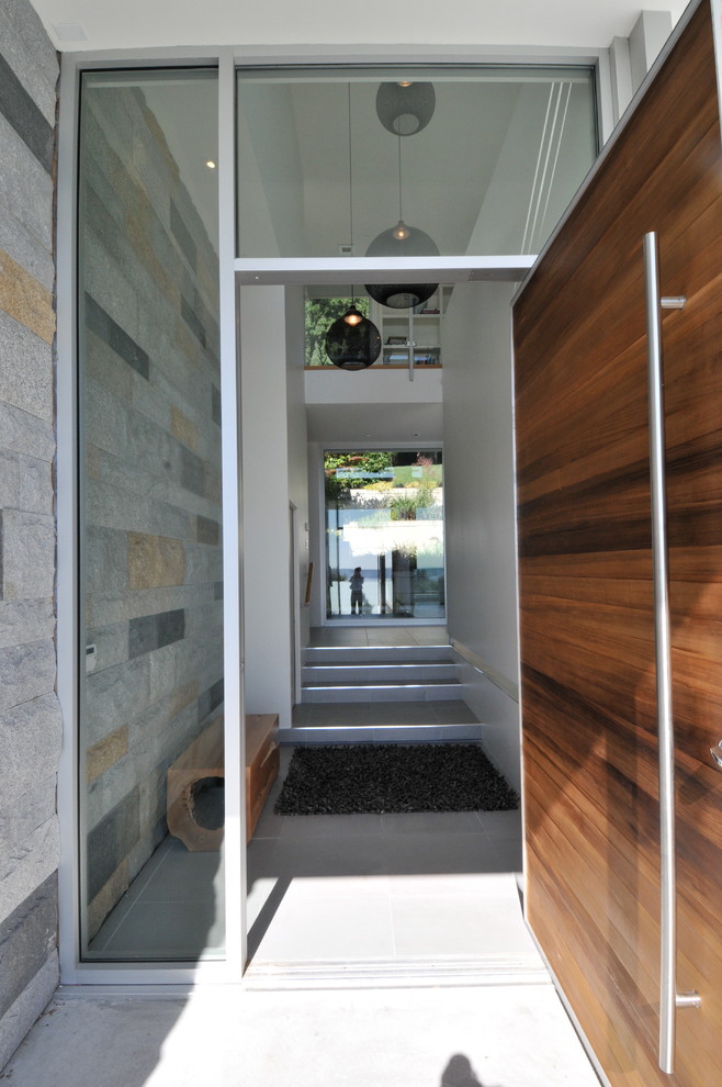 バンクーバーにあるコンテンポラリースタイルのおしゃれな玄関ドア (マルチカラーの壁、磁器タイルの床、木目調のドア) の写真