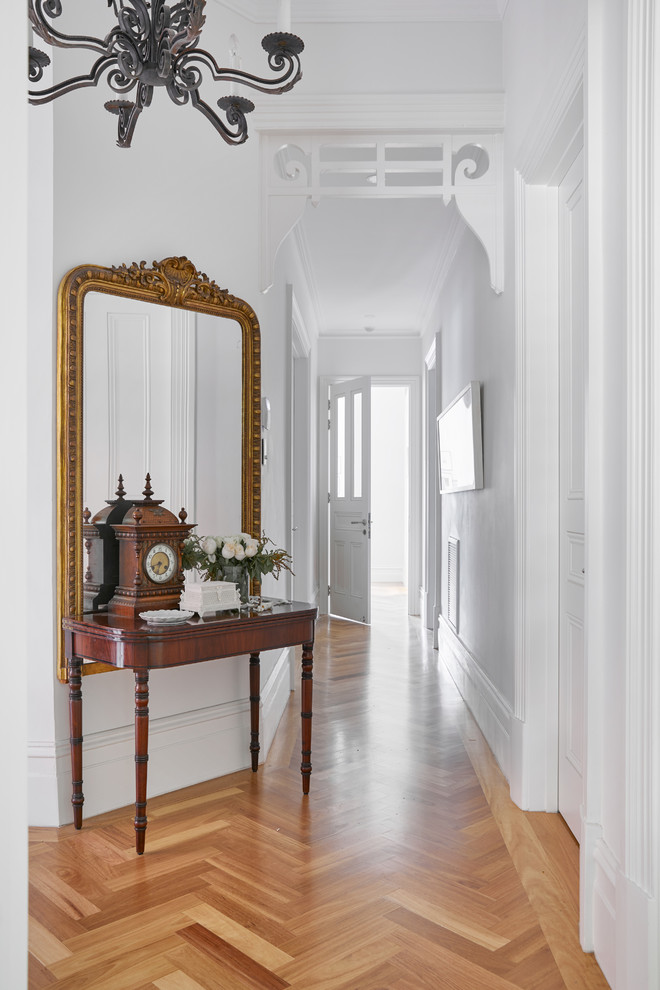 Esempio di un corridoio tradizionale con pareti bianche, pavimento in legno massello medio e pavimento marrone