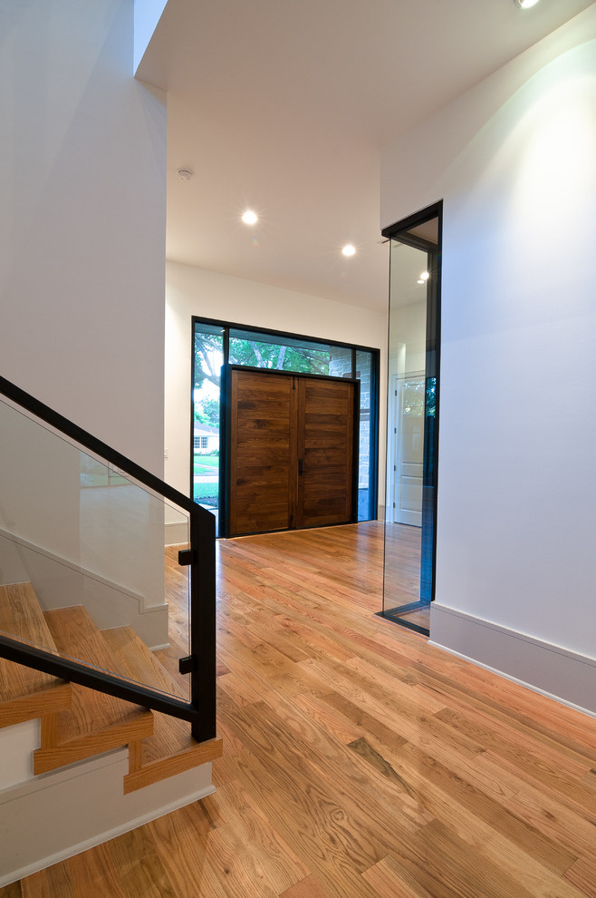 На фото: входная дверь среднего размера в стиле модернизм с белыми стенами, светлым паркетным полом, двустворчатой входной дверью, входной дверью из темного дерева и коричневым полом