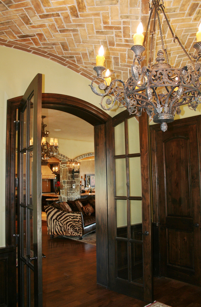 Пример оригинального дизайна: большой вестибюль в средиземноморском стиле с коричневыми стенами, темным паркетным полом, двустворчатой входной дверью, входной дверью из темного дерева и коричневым полом