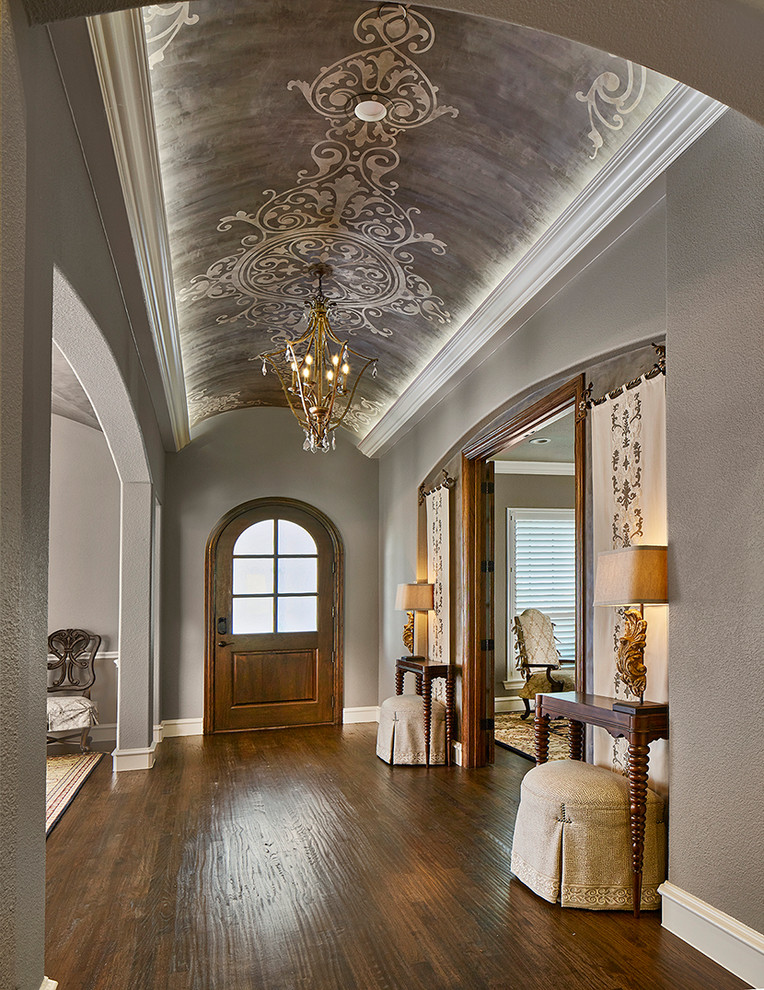 ダラスにあるトラディショナルスタイルのおしゃれな玄関ホール (グレーの壁、無垢フローリング、木目調のドア、茶色い床) の写真