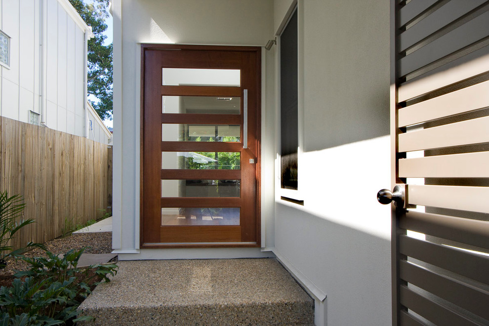 Esempio di un ingresso o corridoio minimalista con pareti bianche, pavimento in cemento, una porta a pivot e una porta in legno scuro