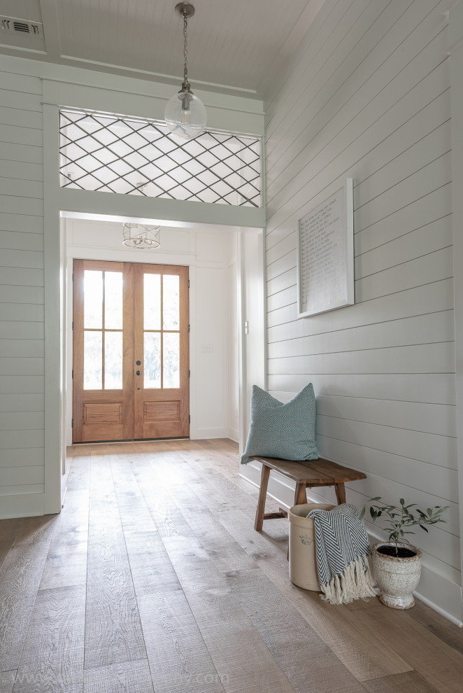 Imagen de entrada de estilo de casa de campo con paredes blancas, suelo de madera clara, puerta doble, puerta de madera en tonos medios, suelo marrón y panelado