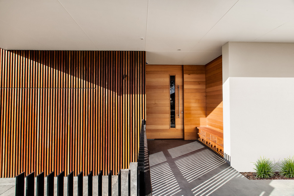 Diseño de entrada contemporánea con paredes blancas, puerta pivotante y puerta de madera en tonos medios