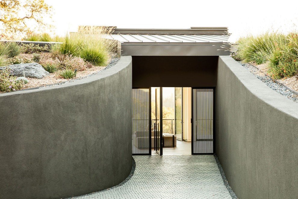 Cette photo montre une grande porte d'entrée tendance avec un mur gris, une porte pivot, une porte en verre et un sol blanc.