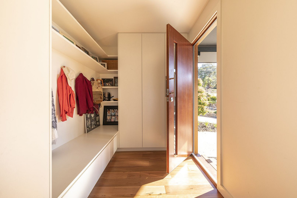 Idee per una piccola porta d'ingresso minimal con pareti bianche, pavimento in bambù, una porta singola e una porta in legno bruno