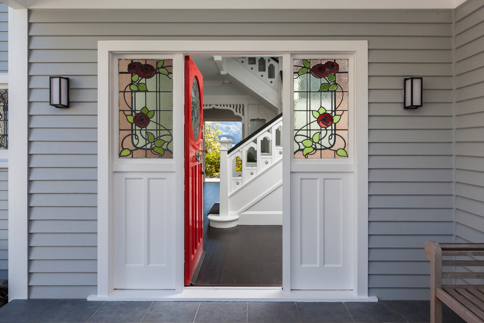 Immagine di una porta d'ingresso classica con pareti grigie, una porta singola, una porta rossa e pavimento grigio