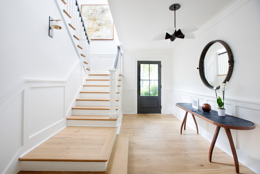 Источник вдохновения для домашнего уюта: фойе в стиле неоклассика (современная классика) с белыми стенами, светлым паркетным полом, одностворчатой входной дверью, черной входной дверью и бежевым полом
