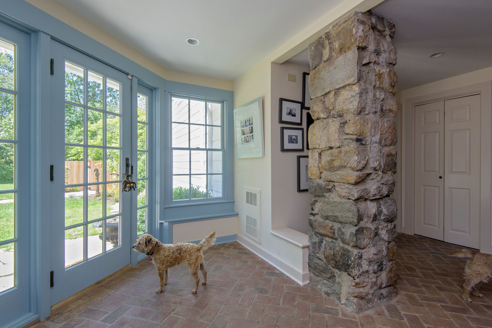 Rustik inredning av en mellanstor foajé, med blå väggar, tegelgolv, en dubbeldörr och en vit dörr