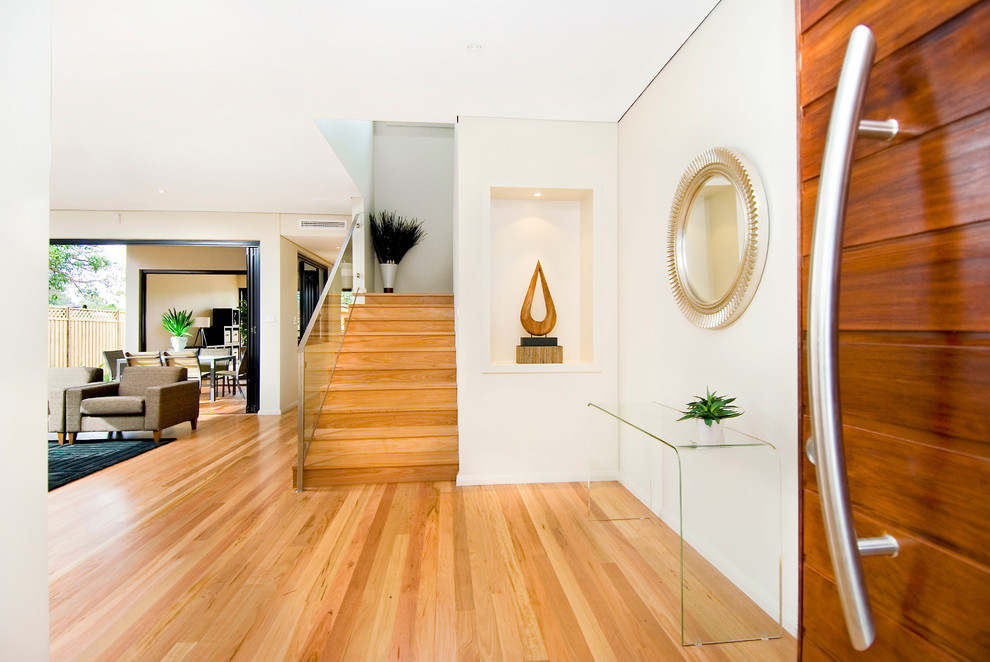 Imagen de entrada contemporánea con suelo de madera clara y puerta de madera en tonos medios