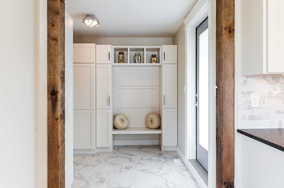 Cette photo montre une entrée tendance de taille moyenne avec un vestiaire, un mur beige, un sol en carrelage de porcelaine, une porte simple, une porte en bois foncé et un sol blanc.