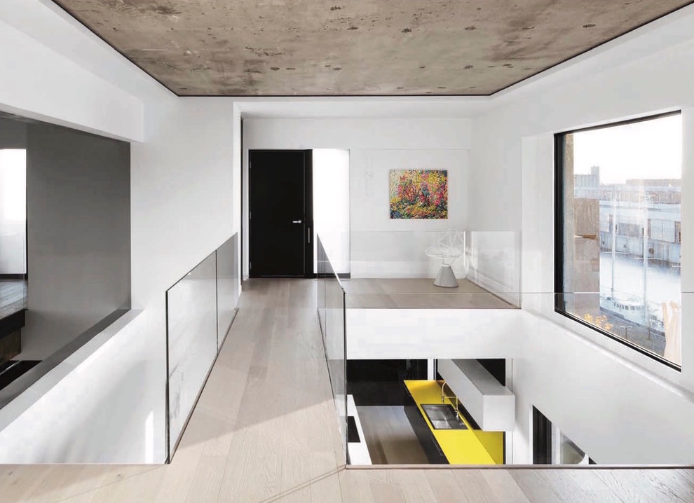 This is an example of a medium sized contemporary hallway in Montreal with white walls, light hardwood flooring, a single front door, a black front door and beige floors.