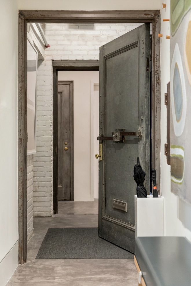 Diseño de puerta principal actual con suelo de cemento, puerta simple, puerta metalizada, paredes blancas y suelo gris