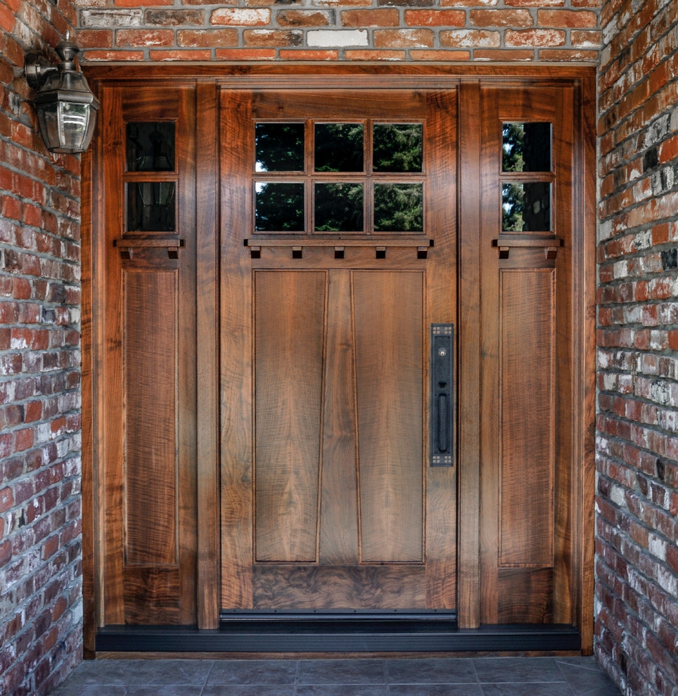 Aménagement d'une porte d'entrée craftsman de taille moyenne avec un mur rouge, un sol en ardoise, une porte simple et une porte en bois brun.