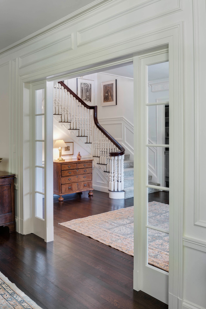На фото: фойе среднего размера в классическом стиле с белыми стенами, темным паркетным полом, одностворчатой входной дверью, белой входной дверью и коричневым полом с