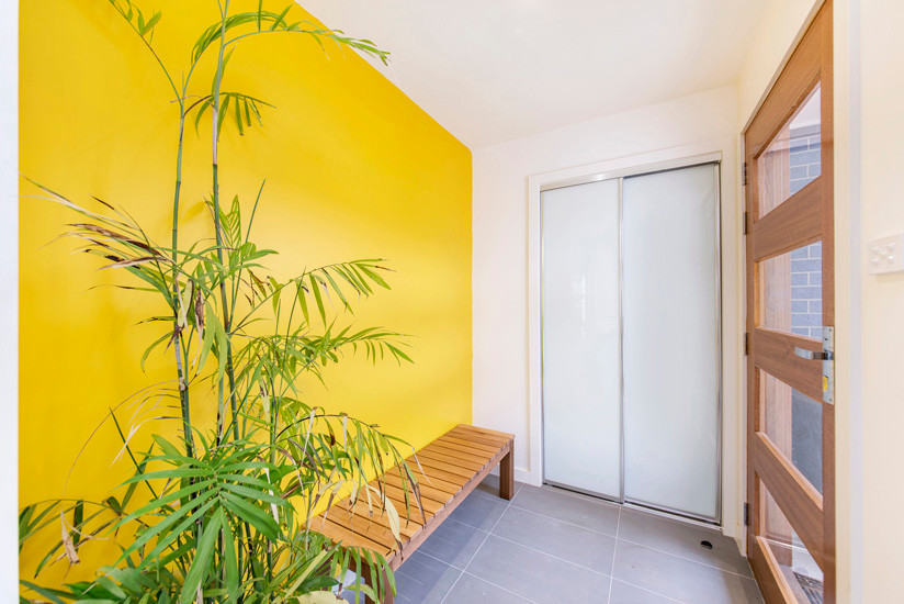 Immagine di un piccolo ingresso con anticamera minimal con pareti gialle, pavimento con piastrelle in ceramica, una porta singola e una porta in legno chiaro