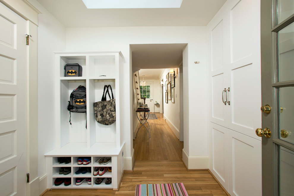 На фото: тамбур среднего размера со шкафом для обуви в стиле неоклассика (современная классика) с белыми стенами, одностворчатой входной дверью, серой входной дверью и светлым паркетным полом с