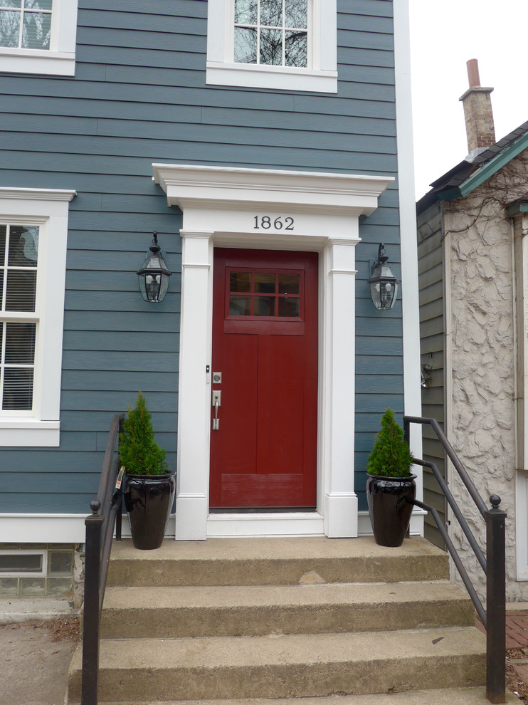 Идея дизайна: входная дверь среднего размера в викторианском стиле с синими стенами, бетонным полом, одностворчатой входной дверью, красной входной дверью и бежевым полом