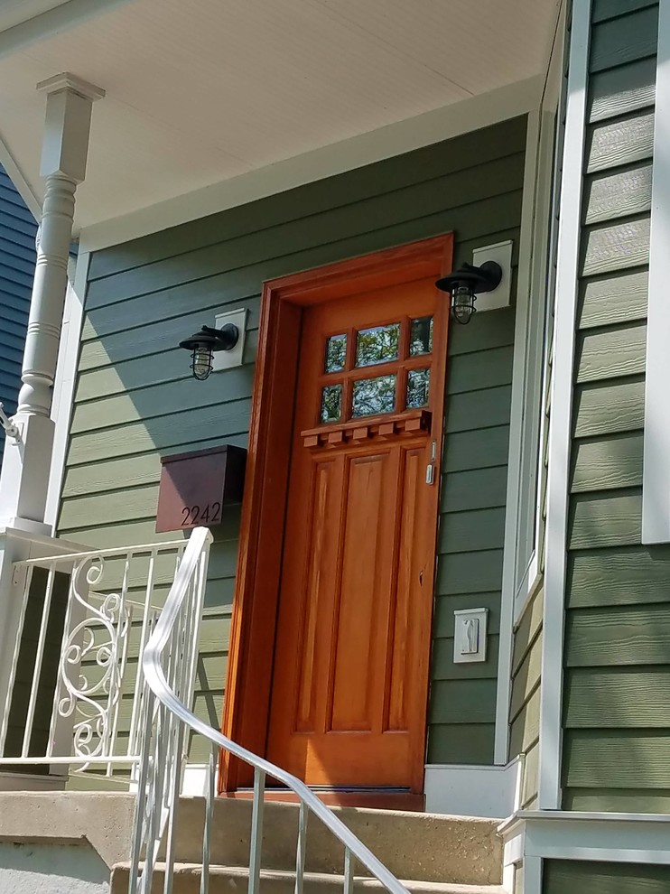 Immagine di una porta d'ingresso vittoriana di medie dimensioni con pareti verdi, pavimento in cemento, una porta singola, una porta in legno bruno e pavimento beige