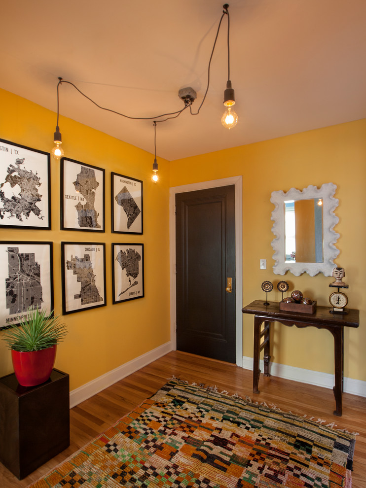 Ejemplo de puerta principal ecléctica de tamaño medio con paredes amarillas, suelo de madera en tonos medios, puerta simple y puerta de madera oscura