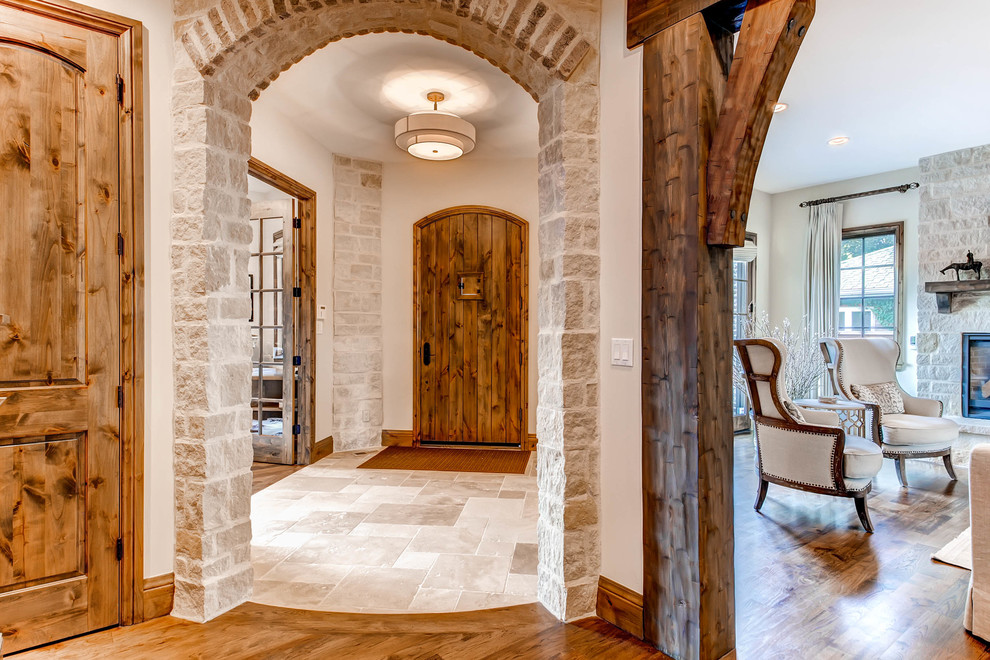 デンバーにあるラグジュアリーな広いトランジショナルスタイルのおしゃれな玄関ラウンジ (白い壁、トラバーチンの床、木目調のドア) の写真