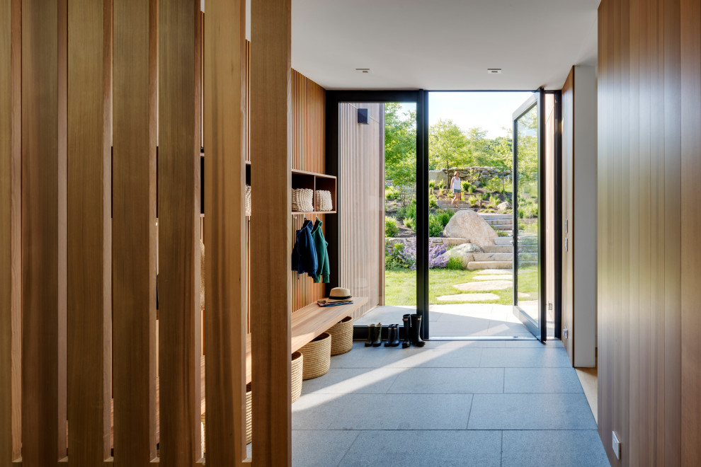 Idées déco pour une grande entrée contemporaine en bois avec un vestiaire, un mur marron, une porte pivot, une porte en verre et un sol gris.