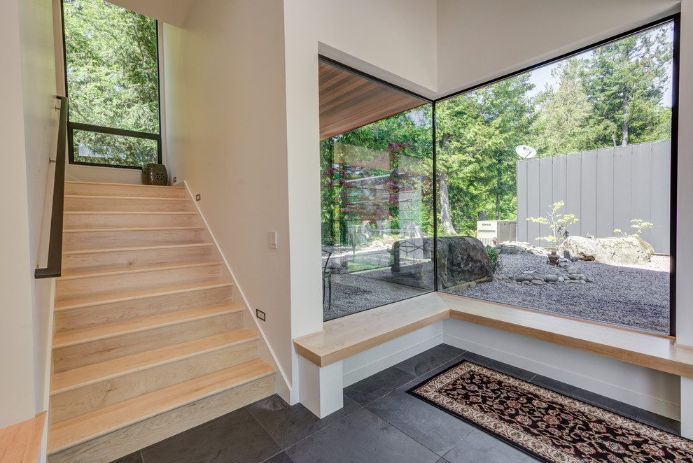 Large modern foyer in Seattle with white walls, slate flooring, a single front door, a light wood front door and black floors.