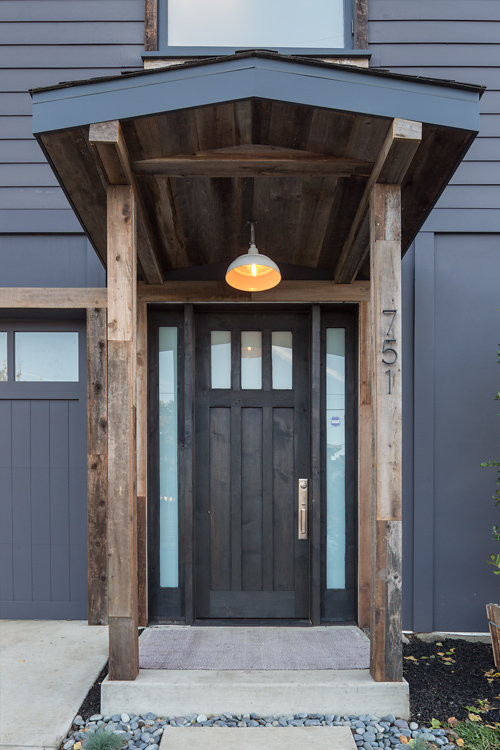 Imagen de puerta principal urbana grande con paredes azules, suelo de cemento, puerta simple y puerta de madera oscura