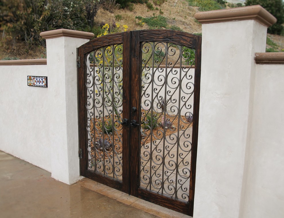 Cette image montre une porte d'entrée méditerranéenne de taille moyenne avec une porte double et une porte marron.