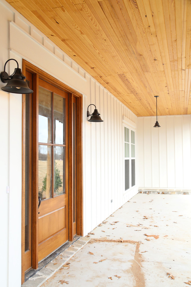 他の地域にある高級な中くらいなカントリー風のおしゃれな玄関ドア (白い壁、コンクリートの床、木目調のドア) の写真