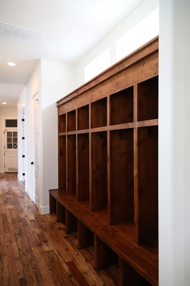 Inspiration for a mid-sized country medium tone wood floor mudroom remodel in Other with white walls