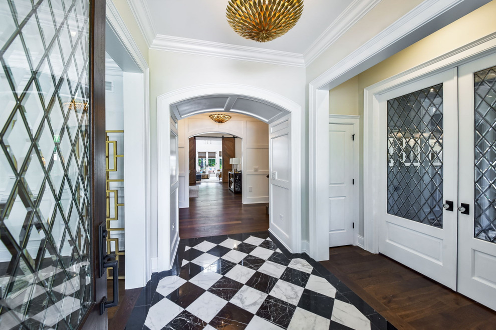 Ispirazione per un ingresso tradizionale di medie dimensioni con pareti bianche, pavimento in marmo, una porta a due ante, una porta in legno scuro, pavimento nero e boiserie