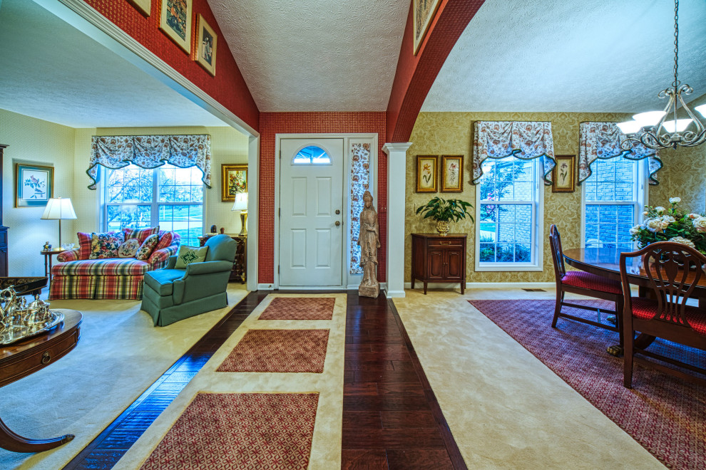 クリーブランドにある高級な中くらいなトラディショナルスタイルのおしゃれな玄関ロビー (赤い壁、濃色無垢フローリング、白いドア、茶色い床) の写真
