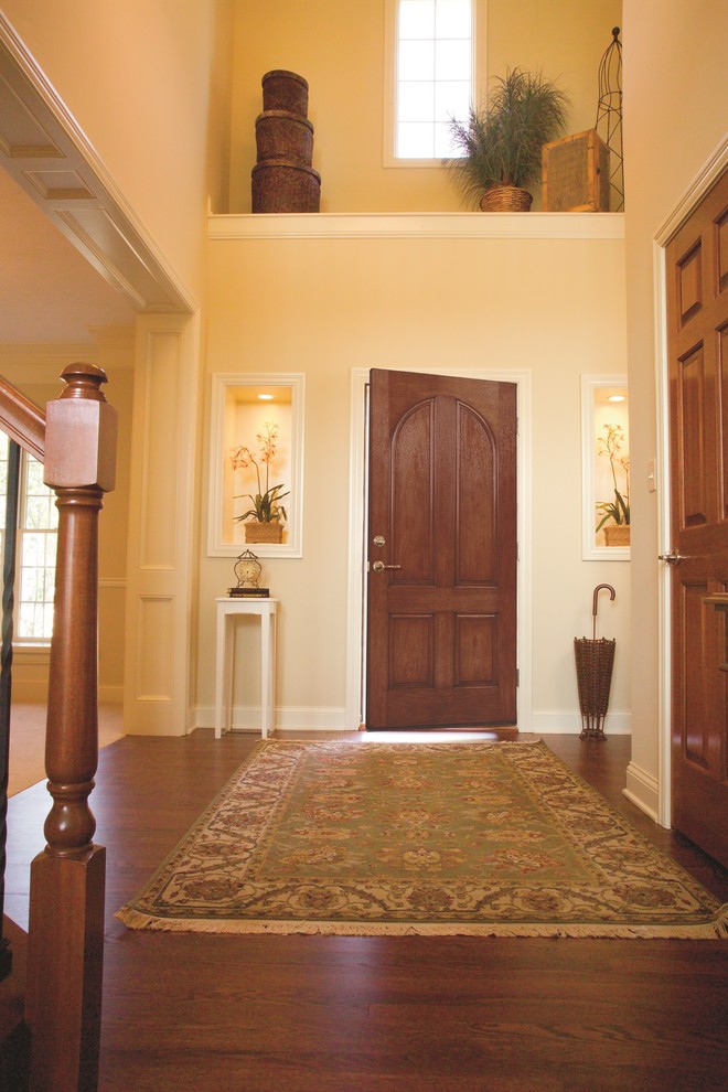Klassisches Foyer mit beiger Wandfarbe, dunklem Holzboden, Einzeltür und dunkler Holzhaustür in Sonstige