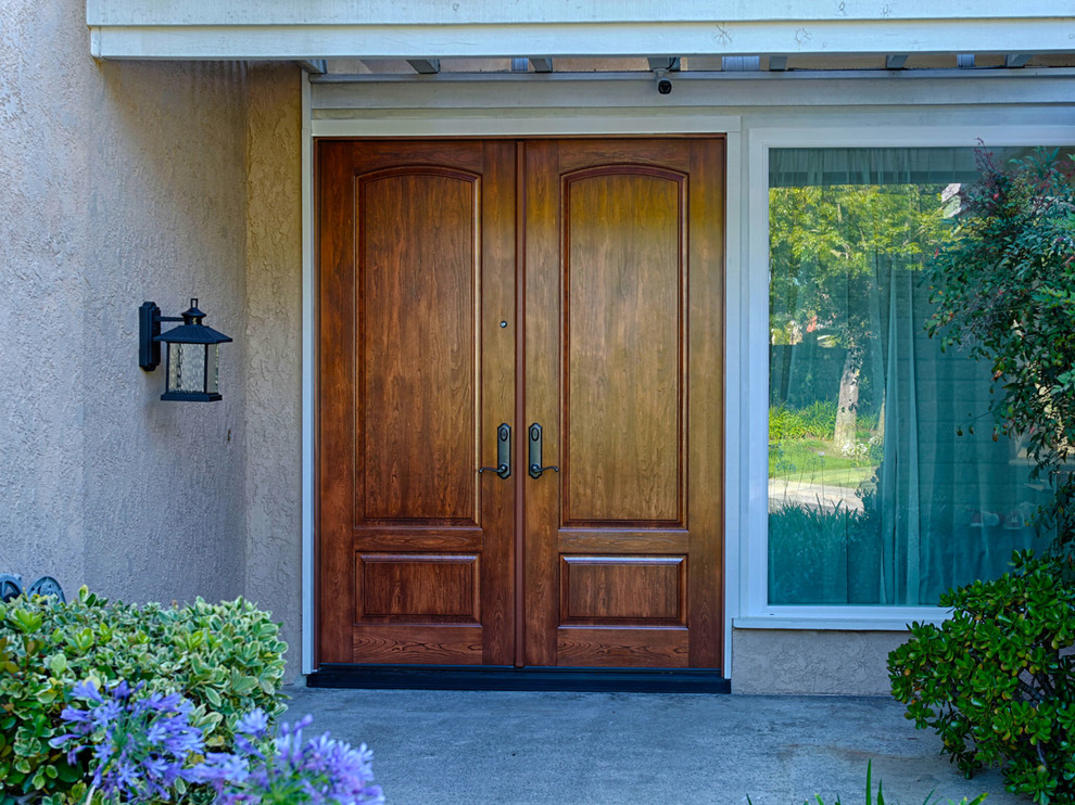 Idée de décoration pour une très grande porte d'entrée tradition avec un mur marron, une porte double et une porte en bois brun.