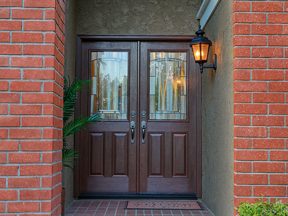 This is an example of a large traditional front door in Orange County with orange walls, a double front door and a medium wood front door.