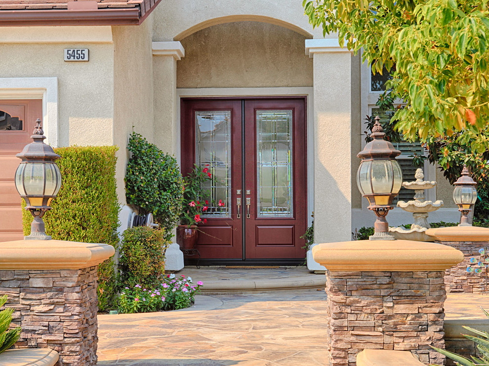 Entryway - huge traditional entryway idea in Orange County with beige walls and a medium wood front door