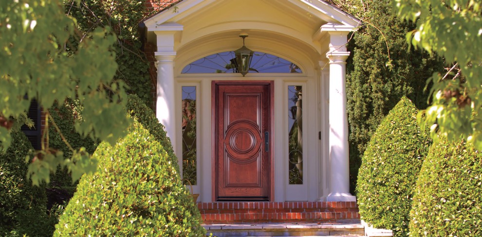Ejemplo de puerta principal tradicional de tamaño medio con paredes blancas, suelo de ladrillo y puerta de madera oscura
