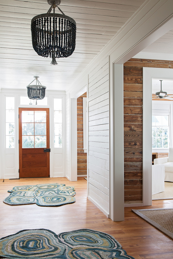 Foto de distribuidor costero con paredes blancas, suelo de madera clara, puerta simple y puerta de madera en tonos medios