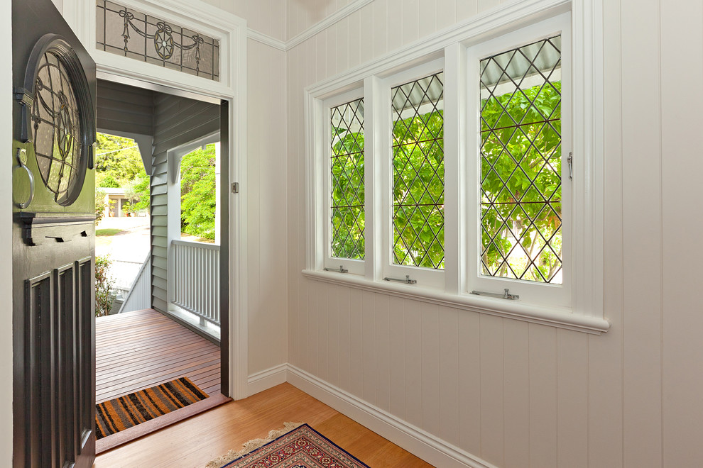 Exempel på en mellanstor klassisk foajé, med vita väggar, ljust trägolv, en enkeldörr och en grå dörr