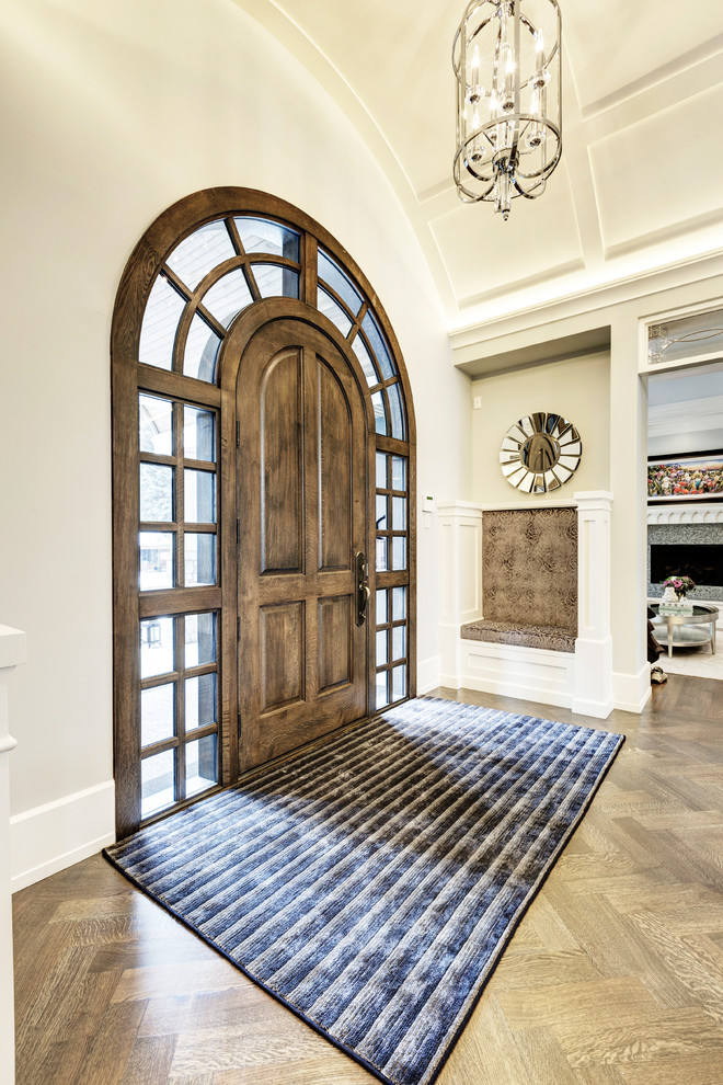 Klassisches Foyer mit weißer Wandfarbe, dunklem Holzboden, Einzeltür und dunkler Holzhaustür in Calgary