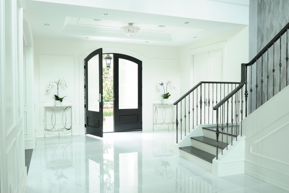 This is an example of a medium sized traditional foyer in Vancouver with white walls, marble flooring, a double front door and a dark wood front door.