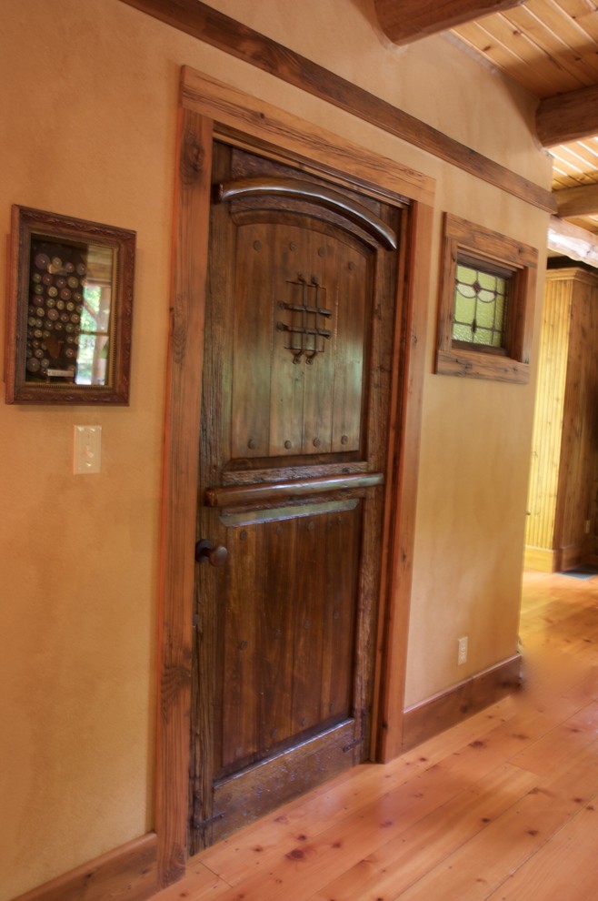 Immagine di un corridoio stile rurale di medie dimensioni con pareti marroni, pavimento in legno massello medio, una porta singola e una porta in legno bruno