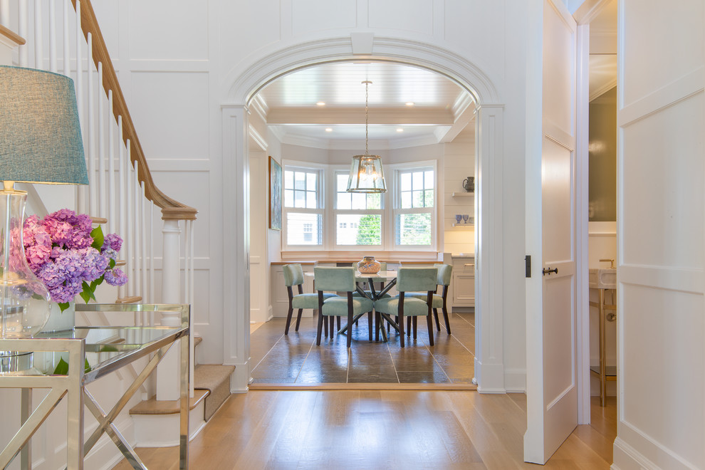 Example of a mid-sized beach style light wood floor and brown floor entryway design in New York with white walls and a white front door